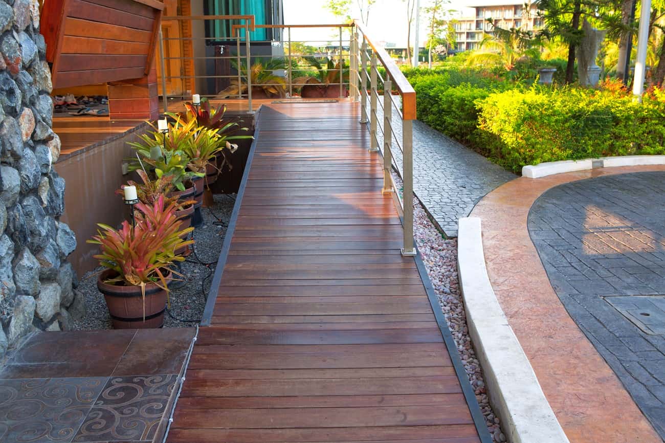 Wooden wheelchair ramp with handrails leading to a house entrance
