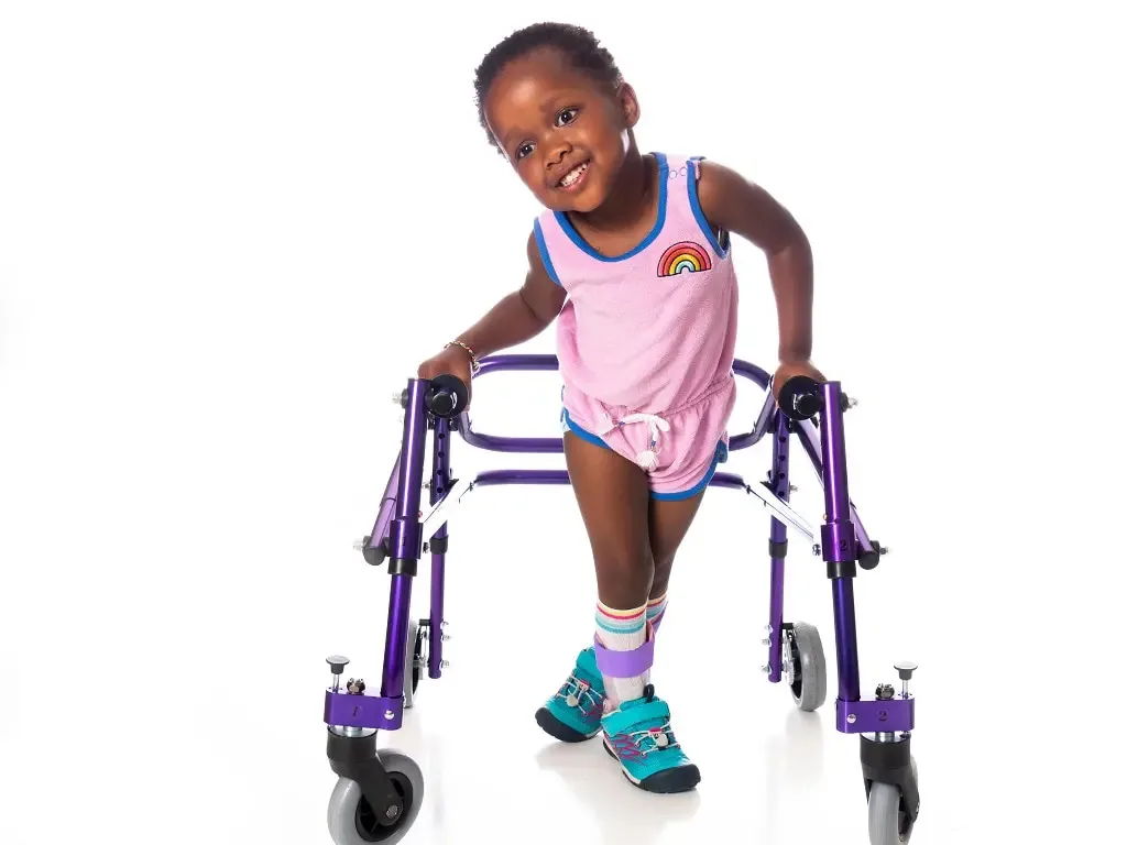Smiling young girl with leg braces walking with a purple walker