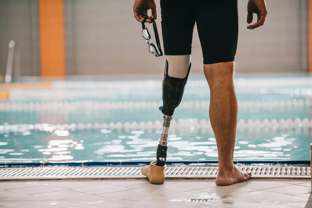 Swimmer with a below-knee prosthetic leg standing at the edge of a pool