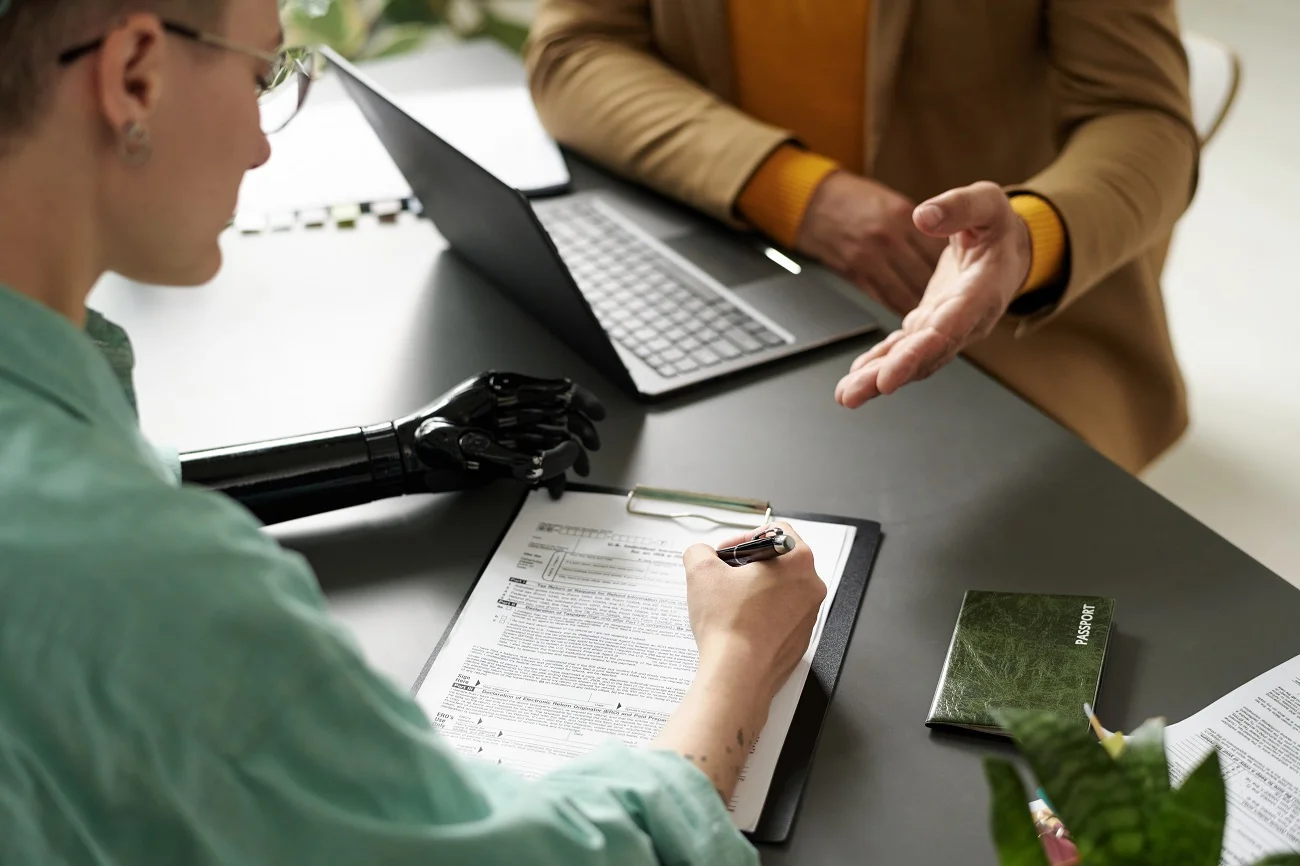 Una persona con una prótesis de mano está revisando documentos de seguros en un escritorio.