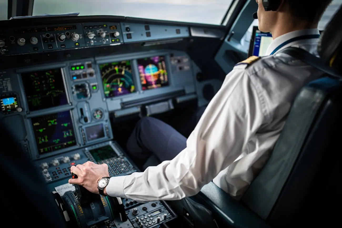 Pilot in uniform at the controls of an airliner cockpit