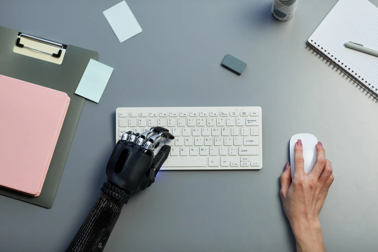 Person with a bionic hand working at a computer keyboard