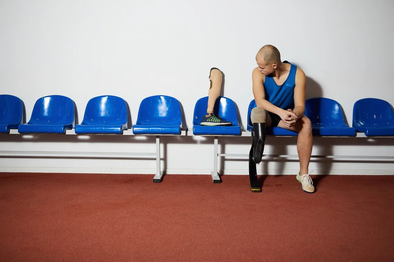 Para athlete with a prosthetic leg sitting on stadium seats