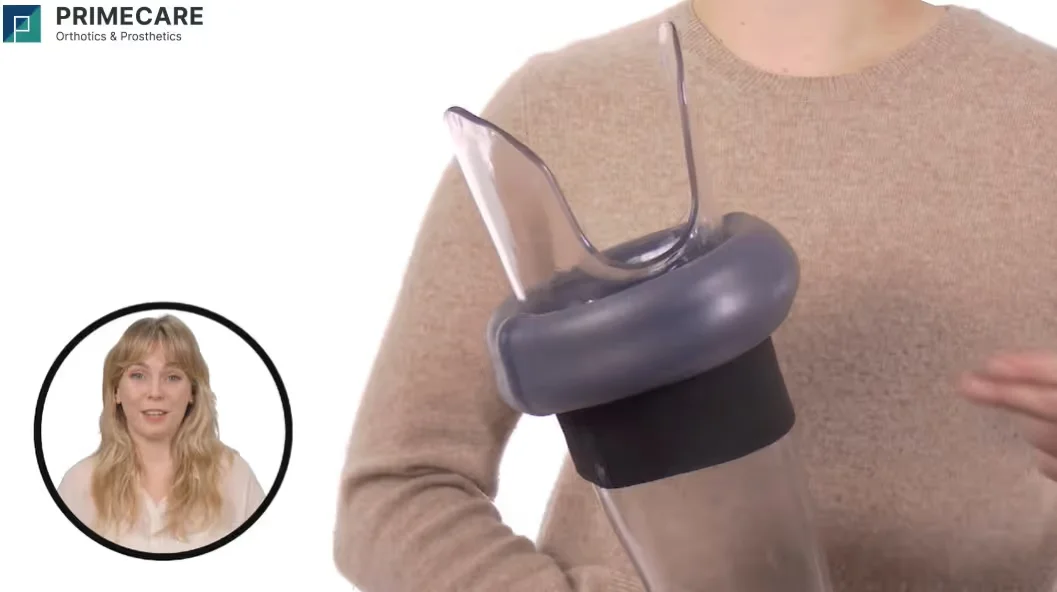 Person in tan sweater holding a clear prosthetic limb component with black and gray parts.