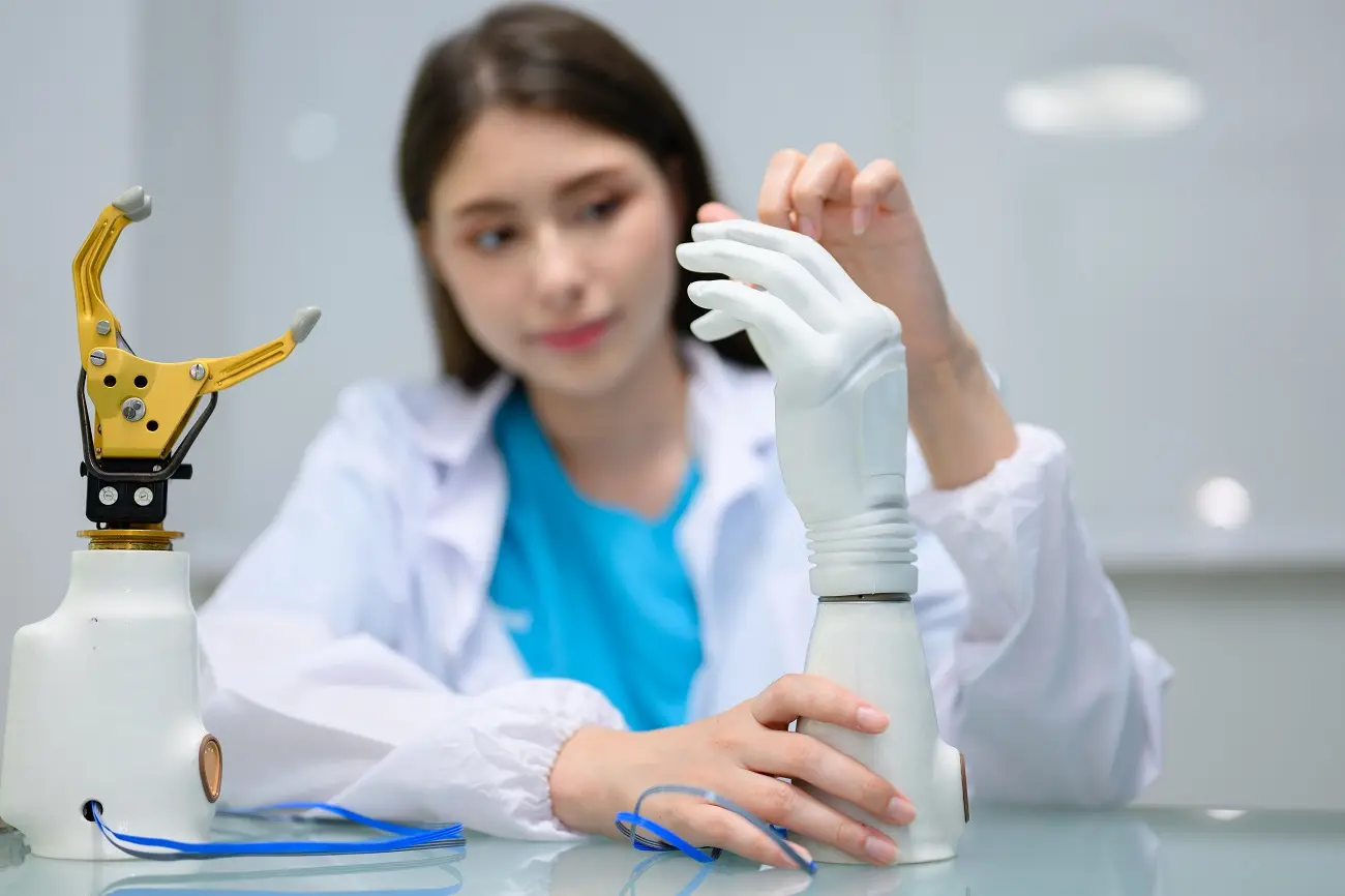 Mujer en una mesa de laboratorio con una mano protésica y un dispositivo terminal de gancho protésico.