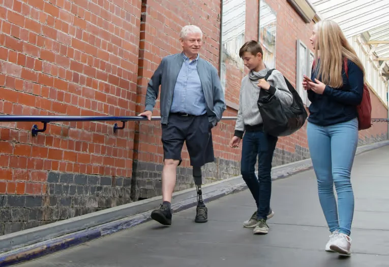 A grandfather with a prosthesis walks with his grandchildren.