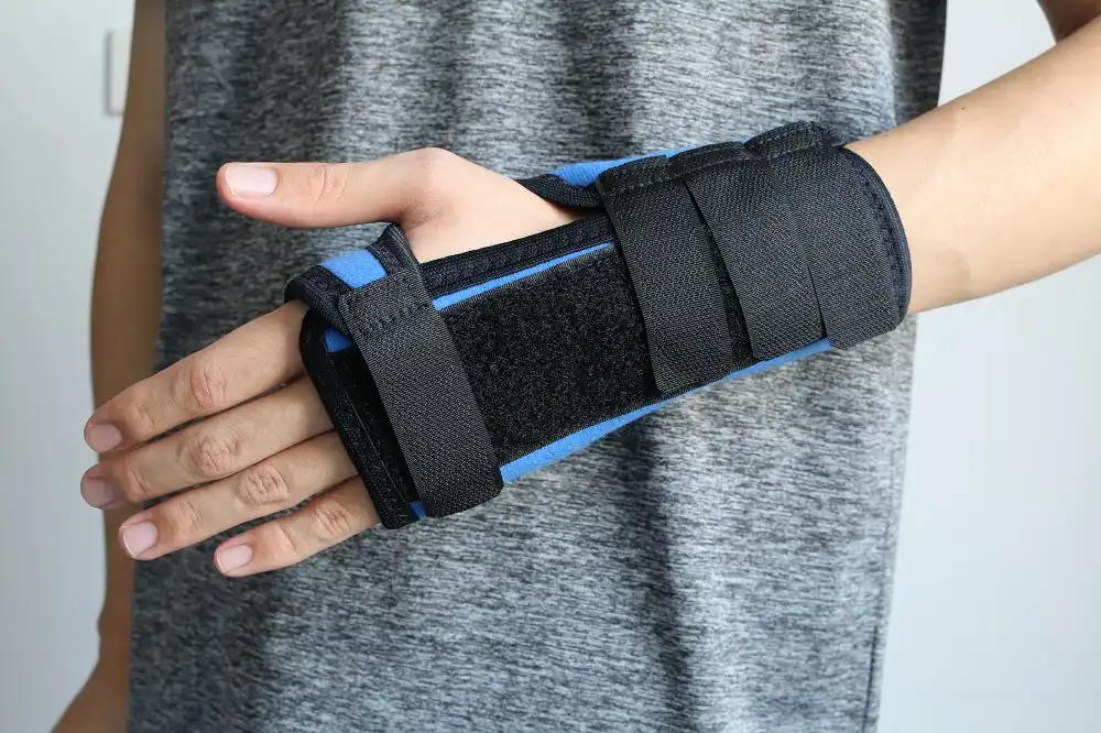 Mano y muñeca inmovilizadas con una férula de muñeca negra y azul.